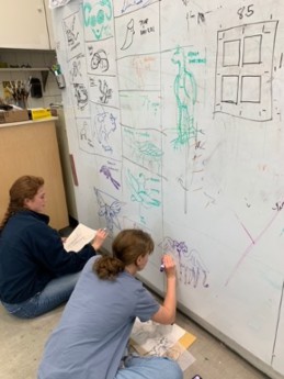Figure 3: Two students sketch out their ideas on the studio white board.